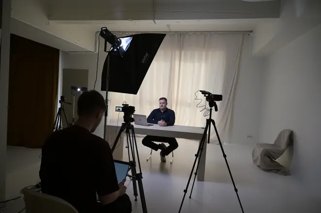 Director behind the camera, founder at the desk in a bright studio
