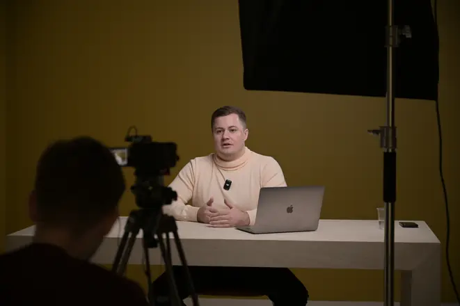 Two-camera setup in a studio with a mustard backdrop