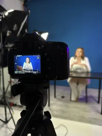Camera monitor shows the frame of an expert in a blue studio