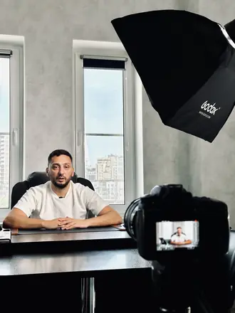 Camera monitor frames a founder at a desk by the window