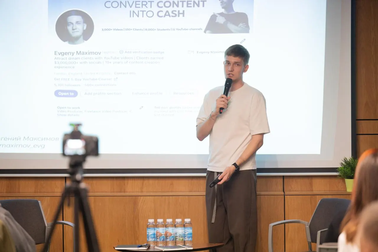 A camera on a tripod filming Evgeny Maximov during his own event