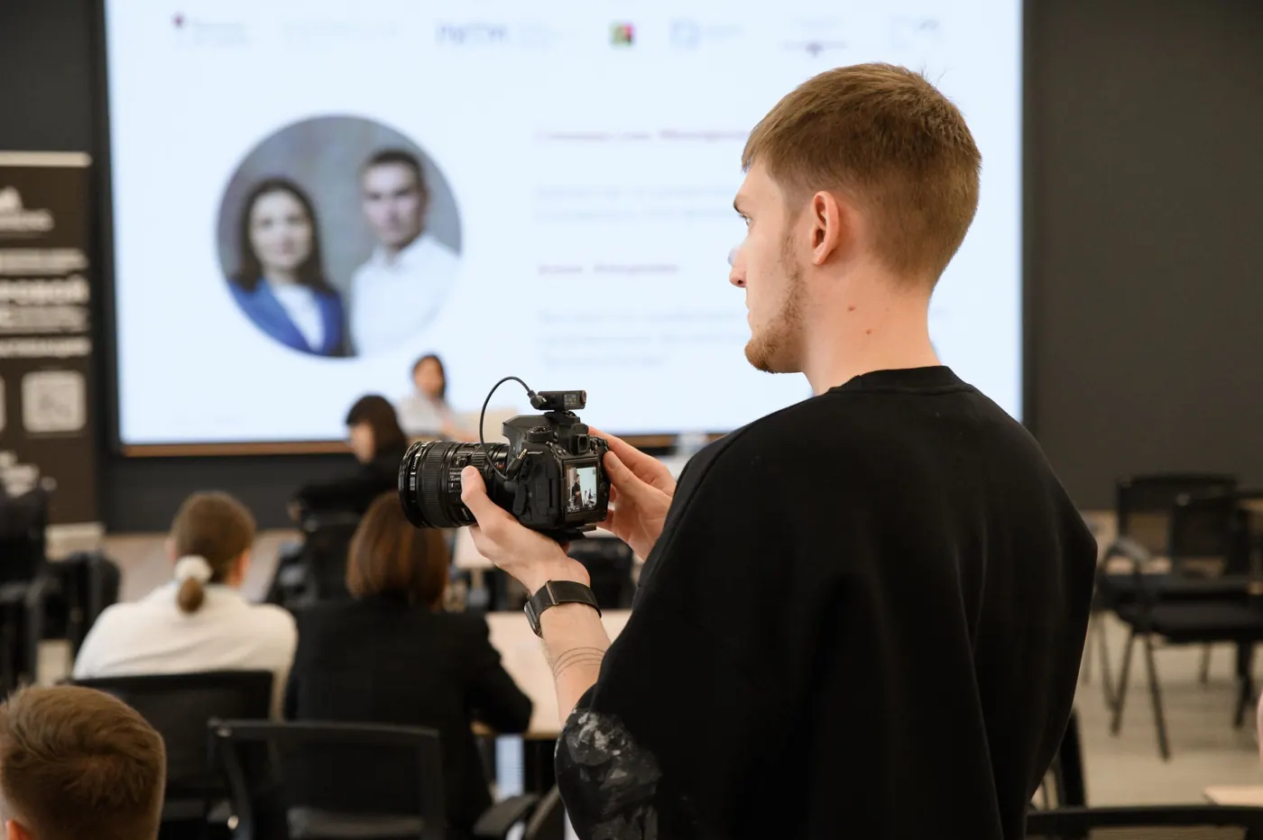 Evgeny Maximov filming a speaker at a business event with a camera