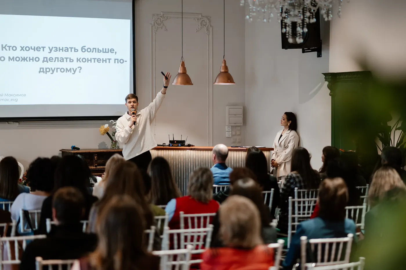 Evgeny Maximov speaking to an audience at a networking event in front of a slide