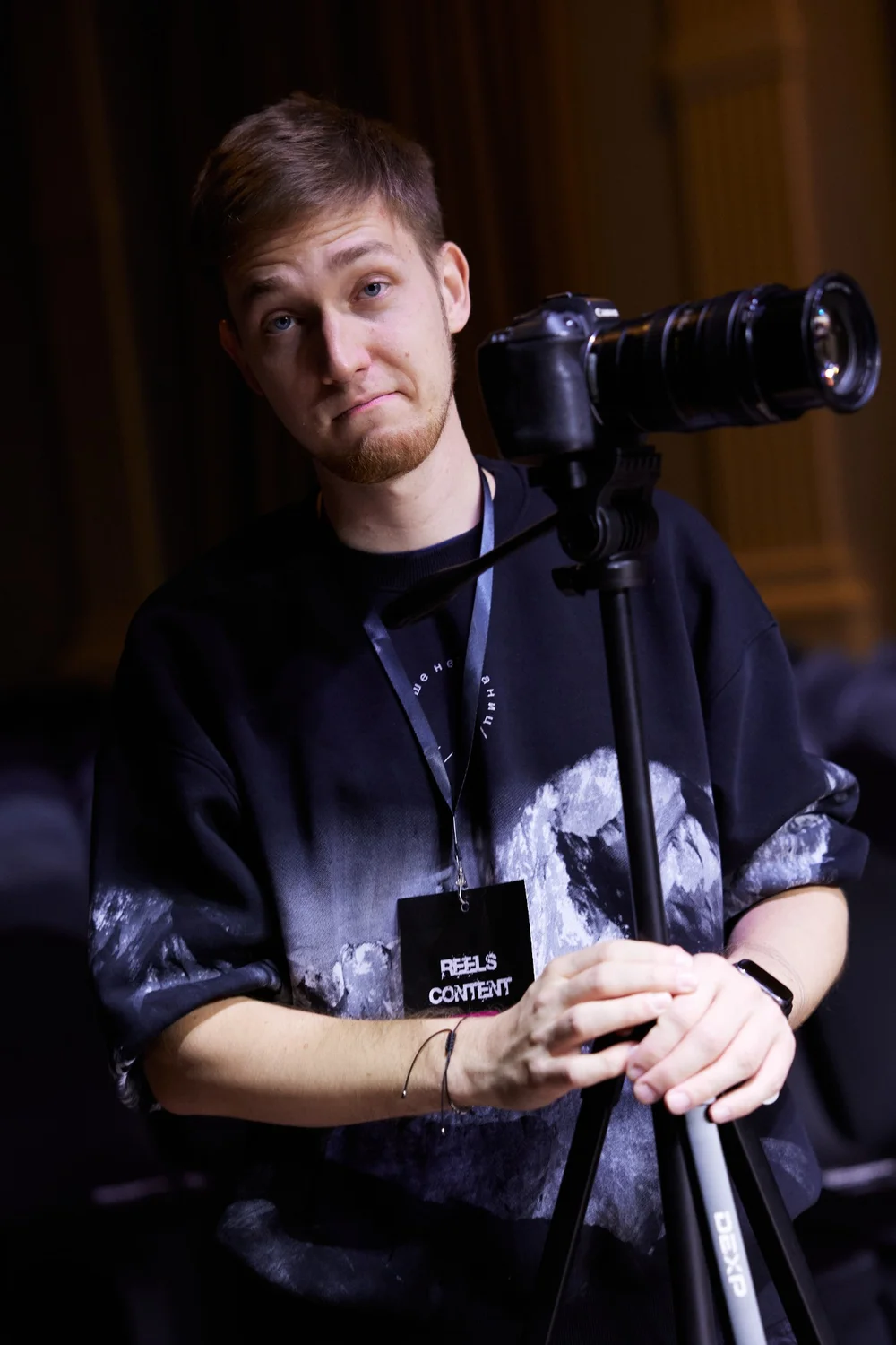 Evgeny Maximov with a camera on a tripod at a business event, wearing a Reels Content badge