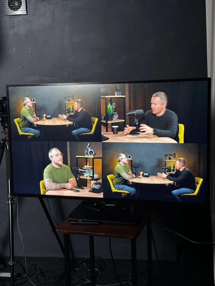 A monitor in the studio showing four views from three cameras: a wide shot of both speakers, a close-up of each speaker and a second wide angle