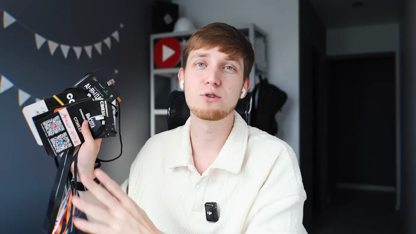 Evgeny Maximov holding a stack of speaker and crew badges from events
