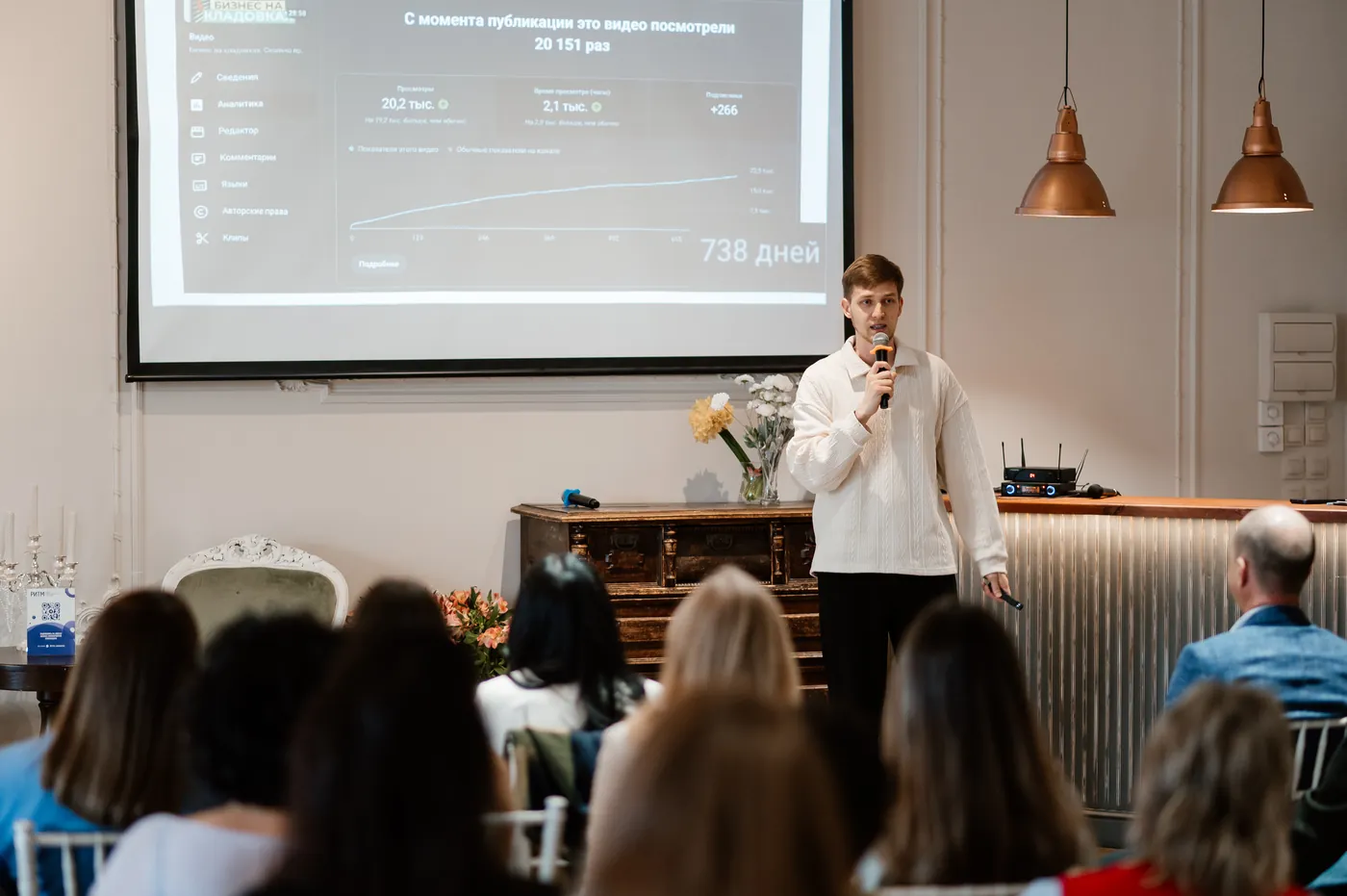 Evgeny Maximov on stage showing the YouTube analytics of a client video to an audience of business owners