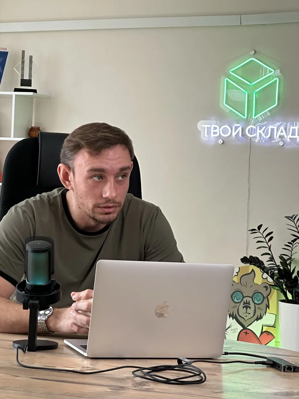 Dmitry Rindevich, founder of Tvoy Sklad, during an office shoot, the green Tvoy Sklad logo on the wall